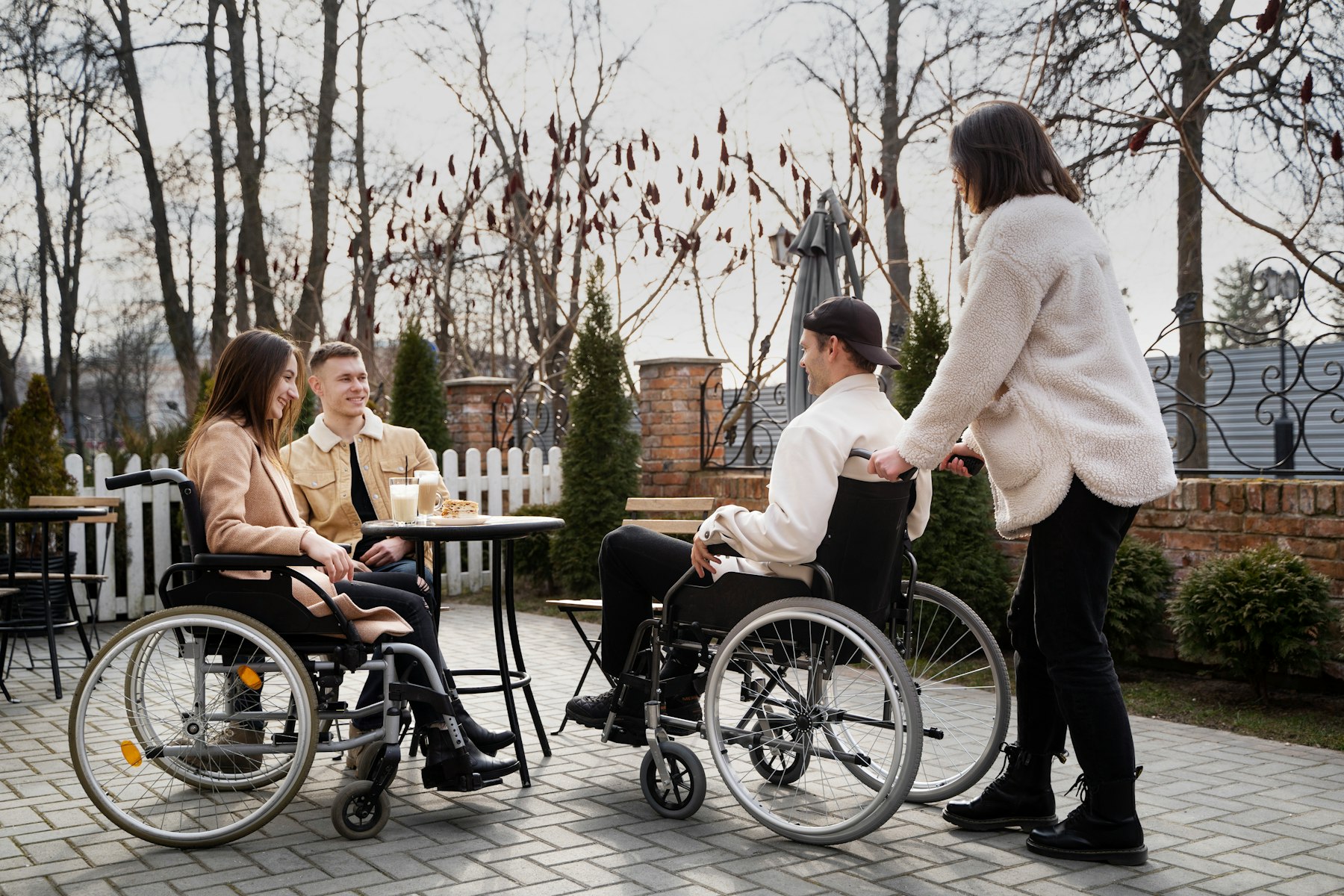 Friends, two using wheelchairs, talking together around an outdoor café table
